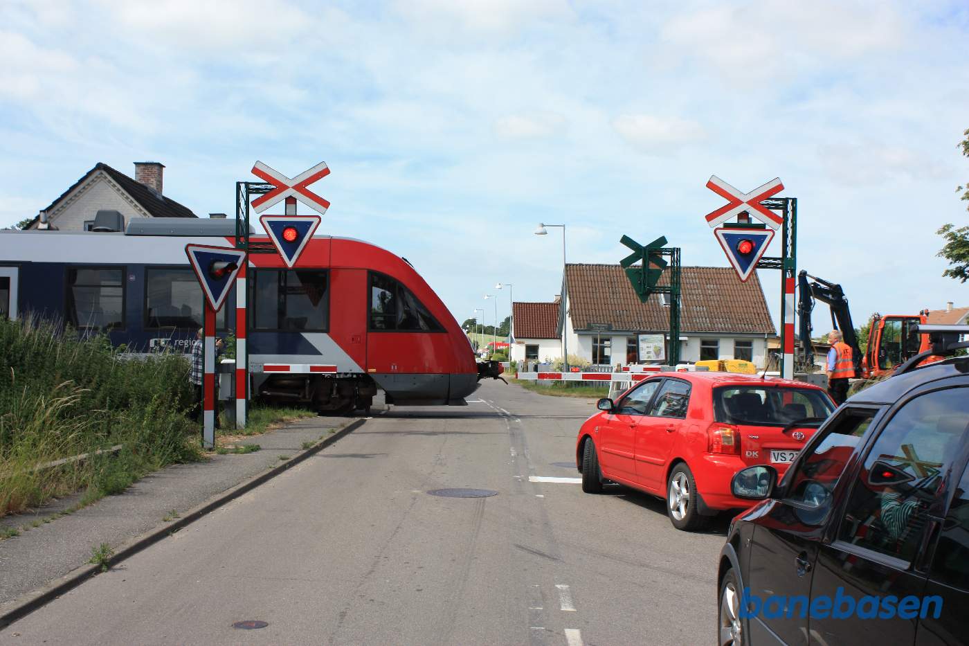 Vi står på Egemosevej og kigger på overkørslen, hvor et Lokaltog netop passerer Vi står på Egemosevej og kigger på overkørslen, hvor et Lokaltog netop passerer