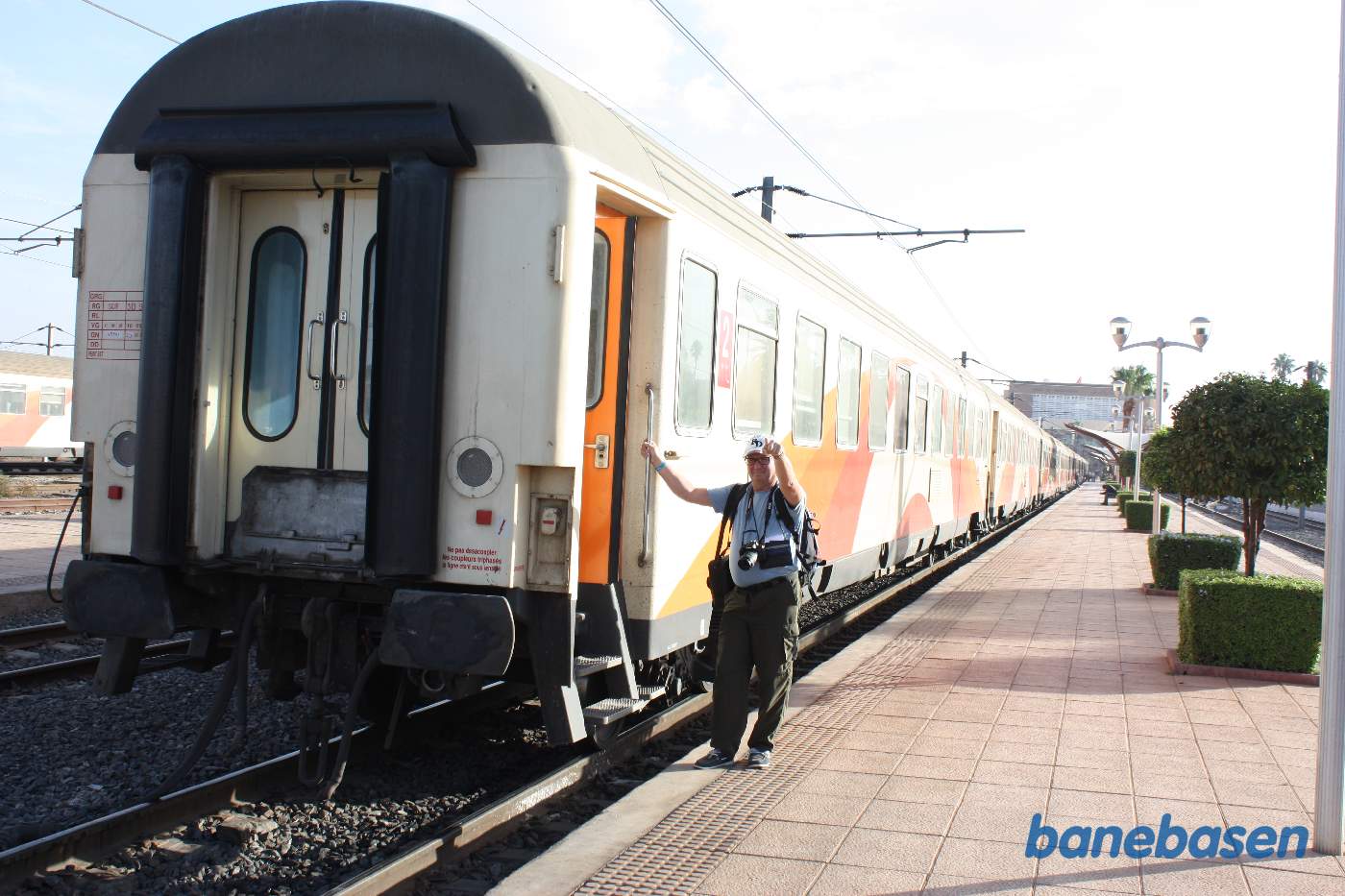 En turist står i døren til et persontog og kigger på fotografen