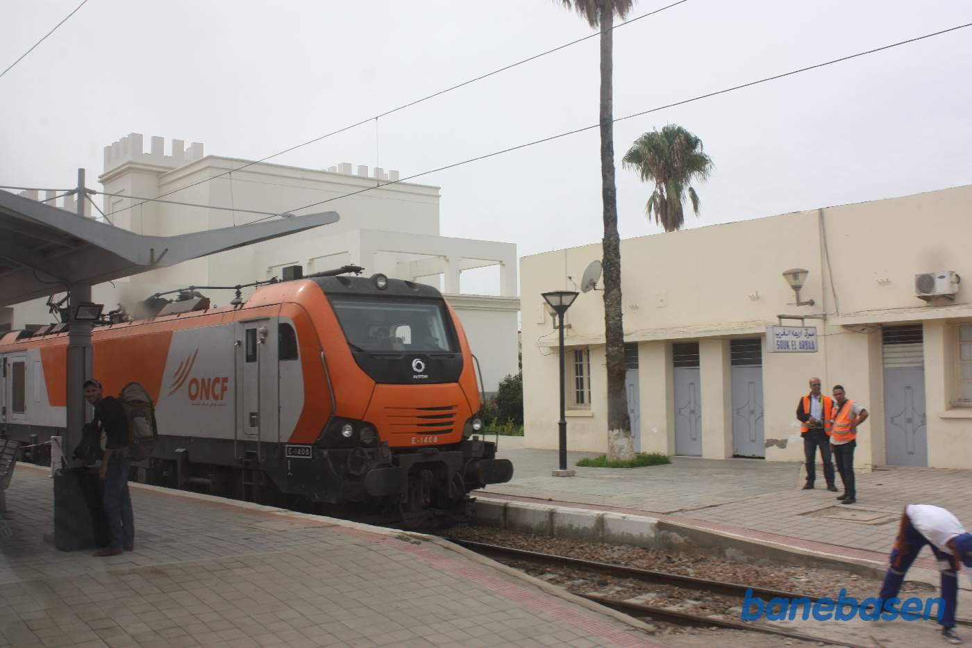 Persontog ved perron, stationsbygningen bag lokomotivet