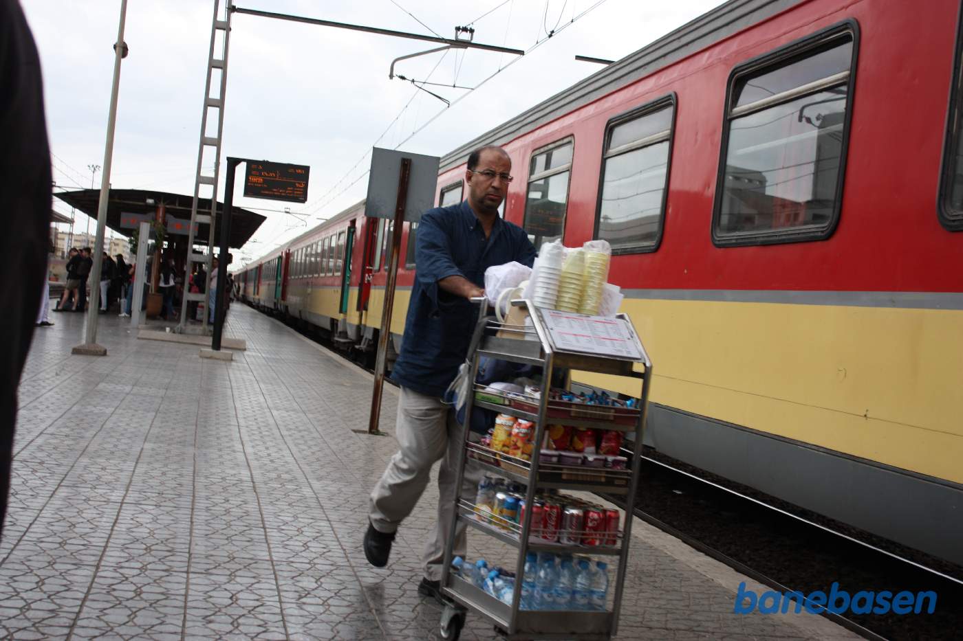 En perronsælger med lille vogn passerer forbi