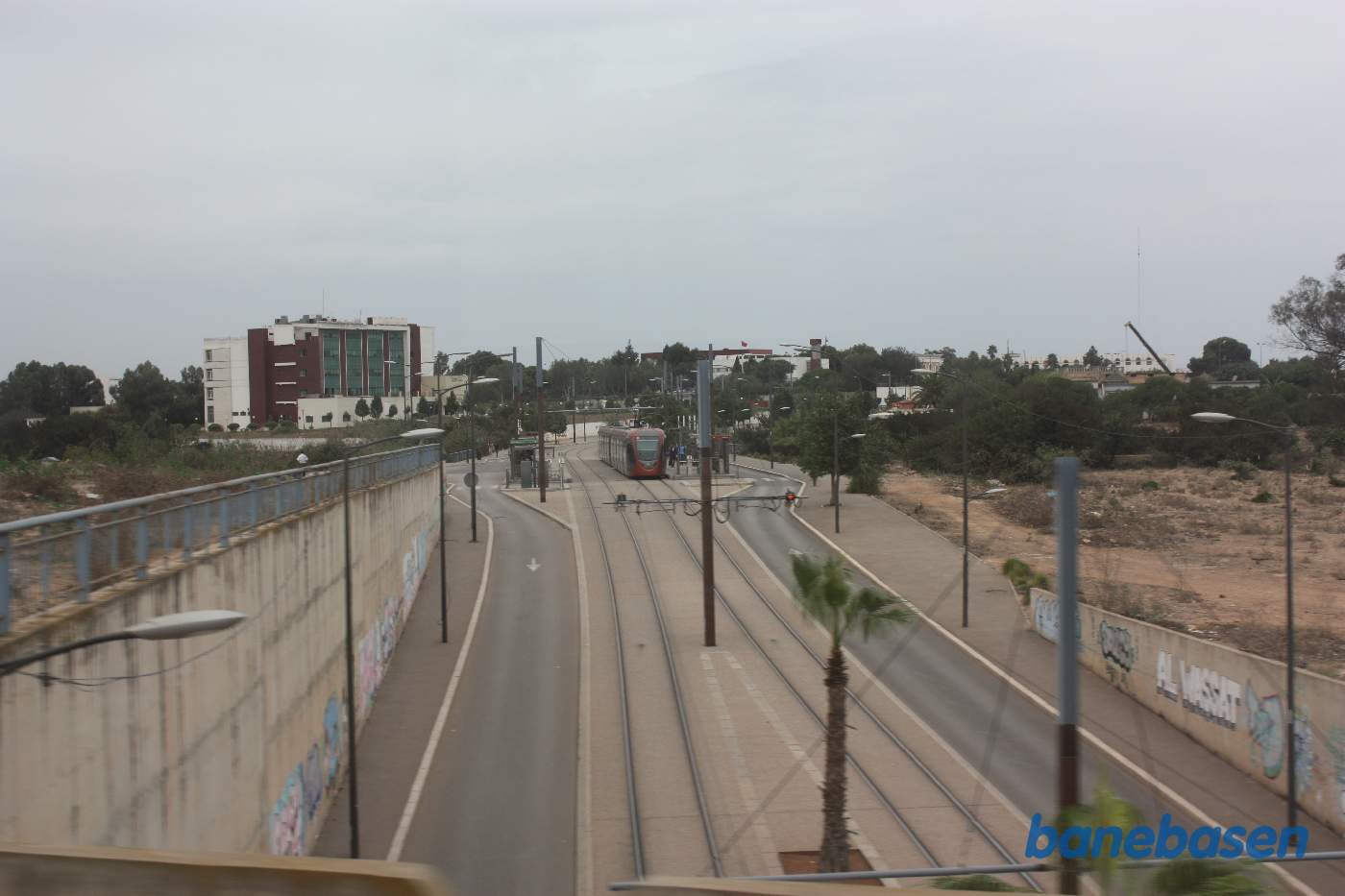 Vi krydser over en vej, hvor sporvognen kører neden under. Sporvognsstoppested længere fremme