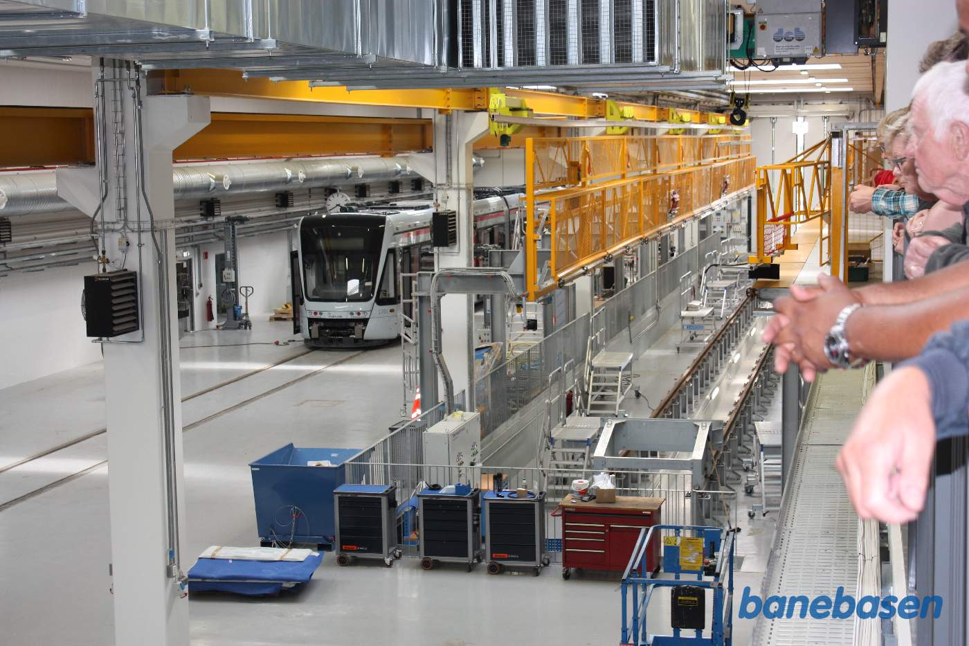 Et vue fra gangbroen ud over værkstedet med et letbanetog i et af sporene Et vue fra gangbroen ud over værkstedet med et letbanetog i et af sporene