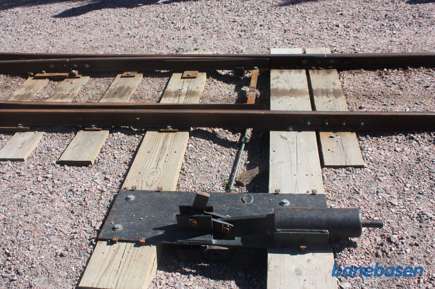 Nærbillede af sporskiftet. Cylinderen med en kraftig fjeder til højre, fastholder tungerne i stabil position