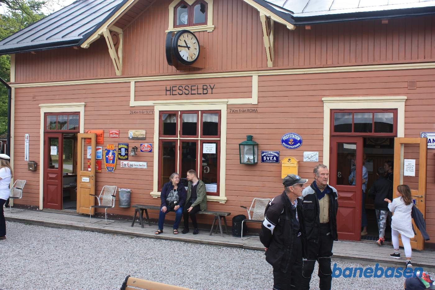 Stationsbygningen med passagerer på perronen
