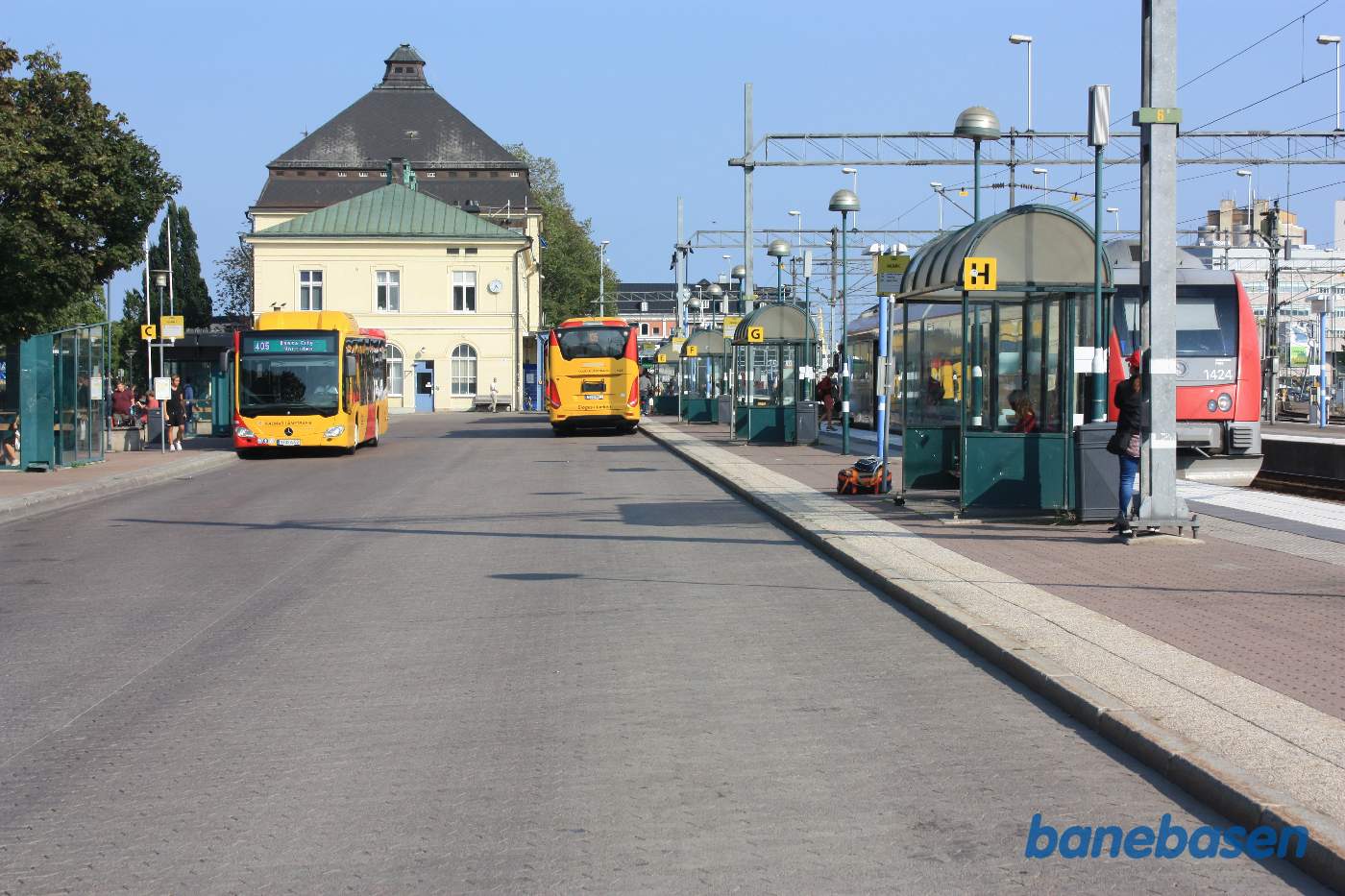 Busholdepladsen med stationsbygningen i baggrunden og perronen til højre