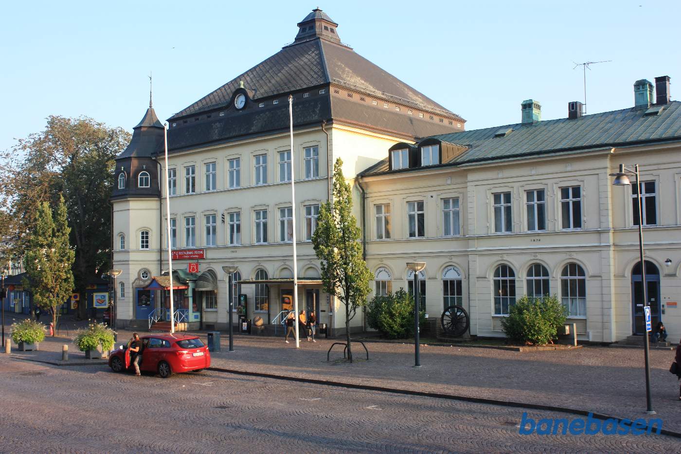 Stationsbygningen set fra vejen, mindesmærkehjulet midt i billedet
