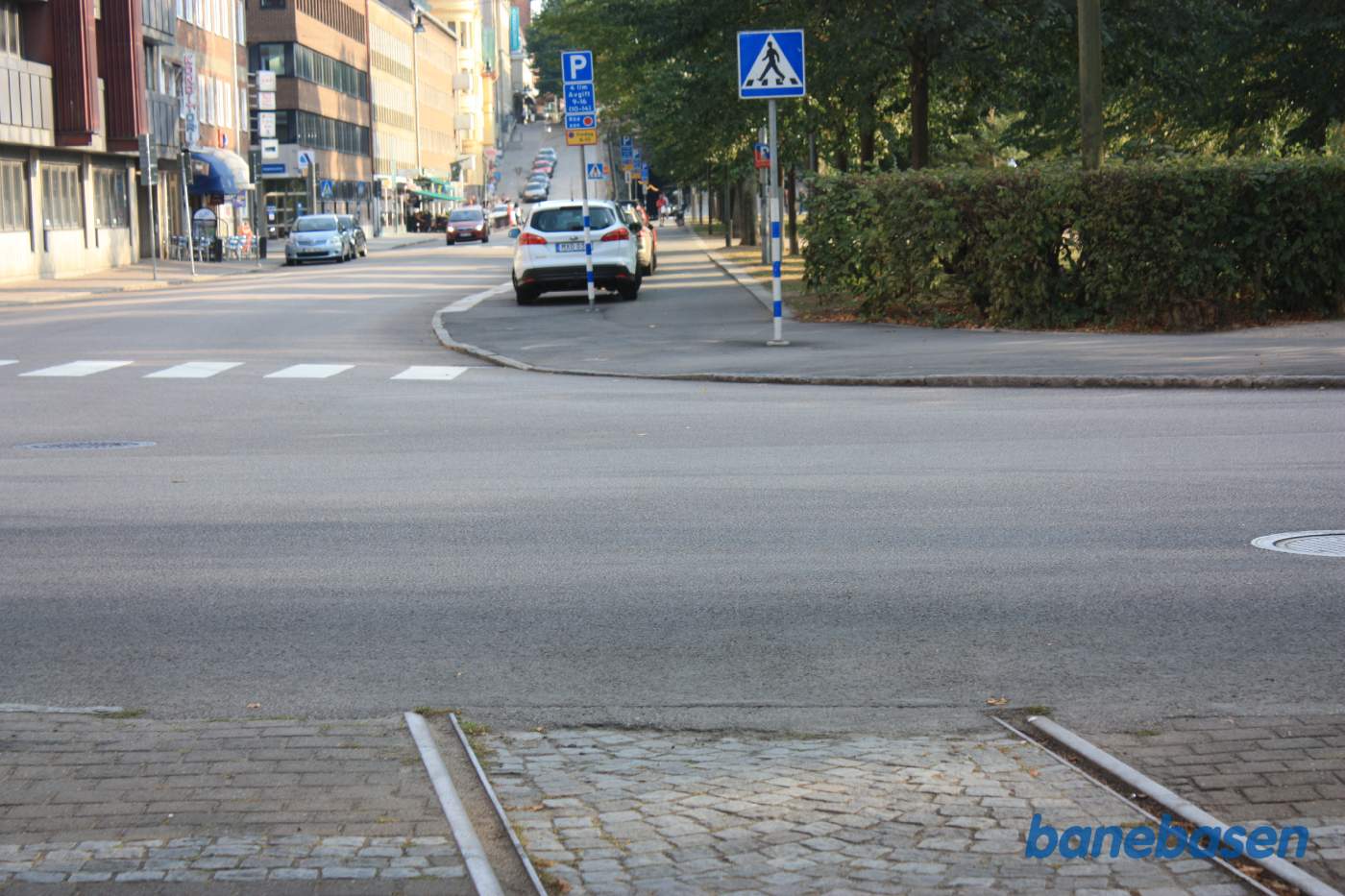 Vi følger resterne af havnebanen, der svinger ned langs gaden, hvor der nu er parkerede biler