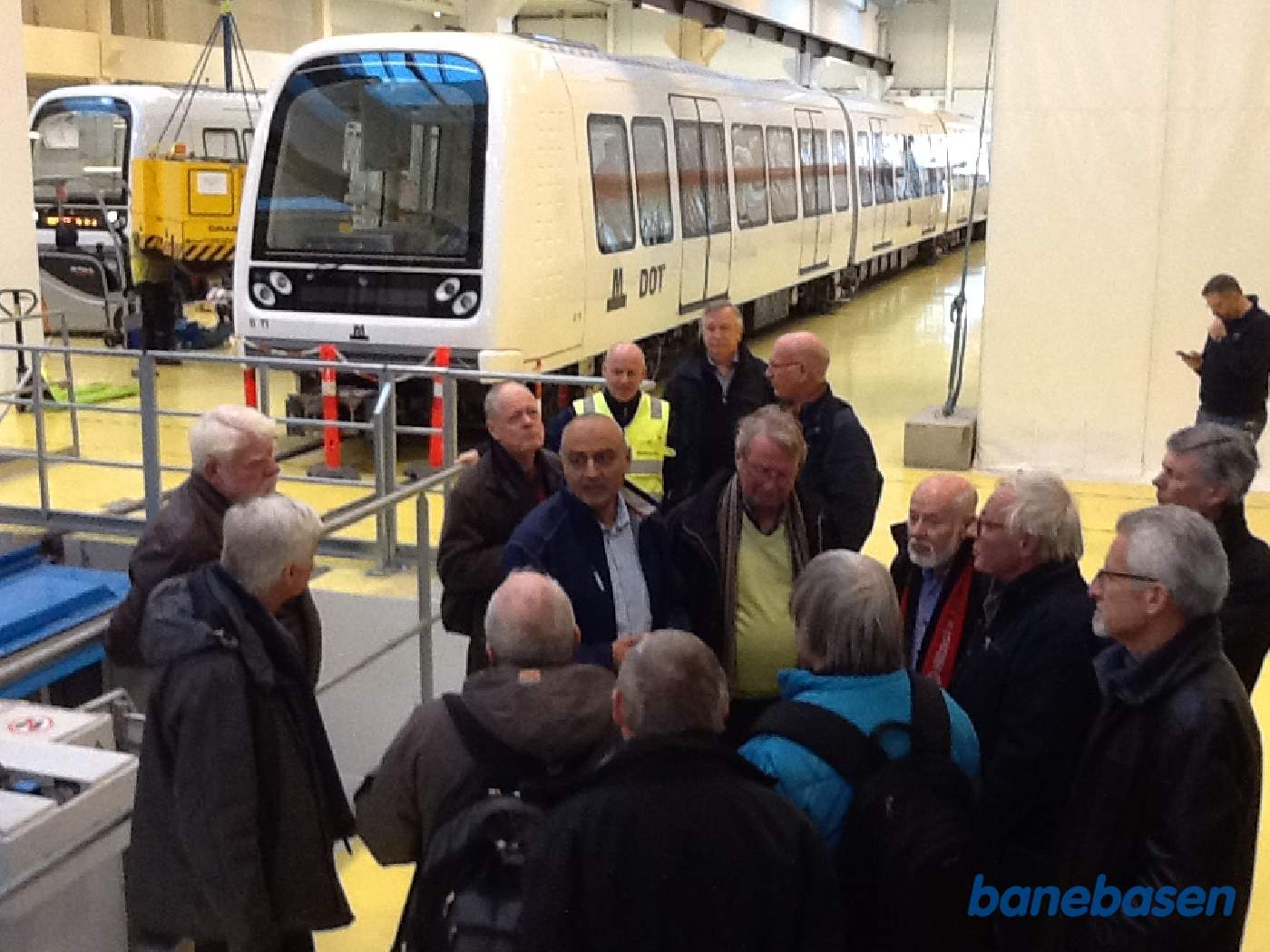 Gæsterne står samlet i remisen med 2 togsæt i baggrunden Gæsterne står samlet i remisen med 2 togsæt i baggrunden