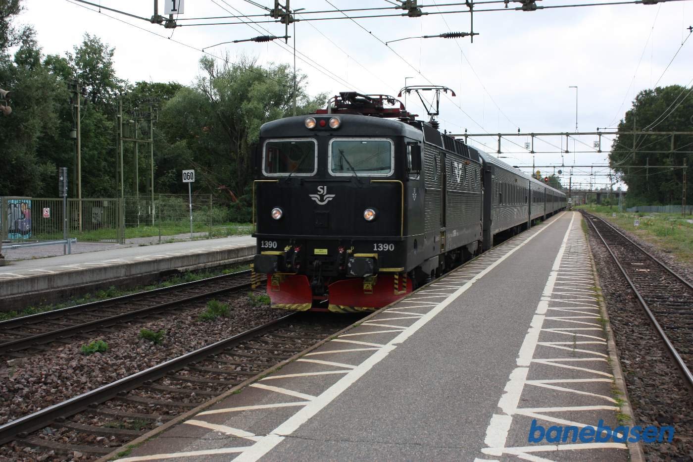 Mens vi venter, kommer et persontog trillende gennem stationen