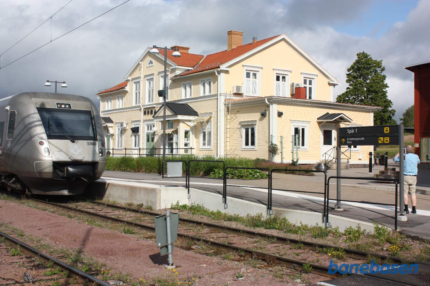 Persontog ved perron med den gamle stationsbygning i baggrunden til højre