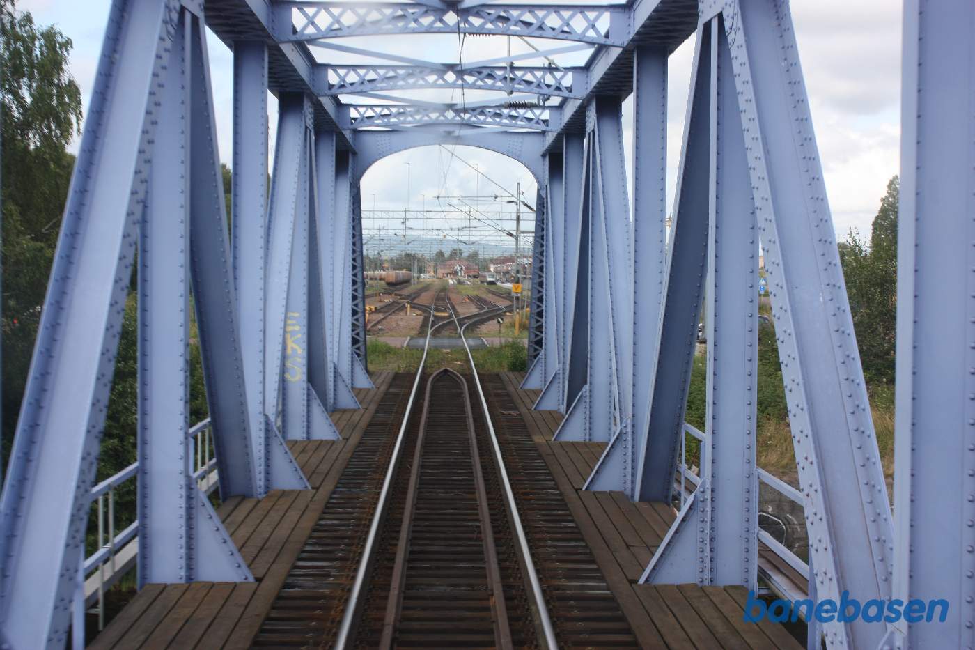 Et bagskud ind over stationen, mens toget langsomt triller ud. Vi kører på broen over elven