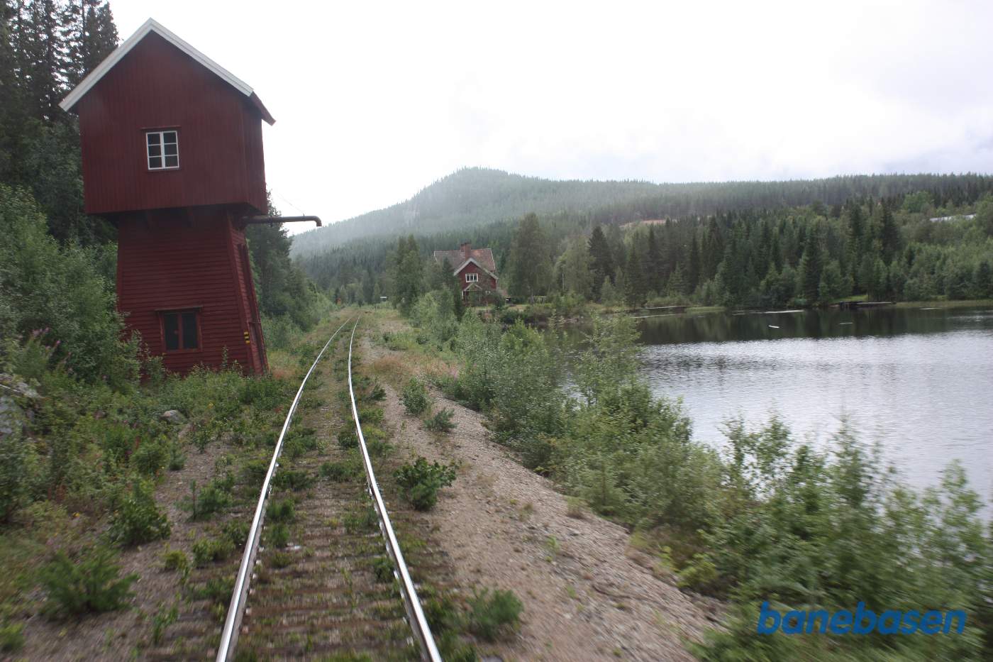 Toget suser igennem Tandsjöborg station, her set ud ad bagruden, vandtårnet ses til venstre og stationsbygningen til højre efter søen