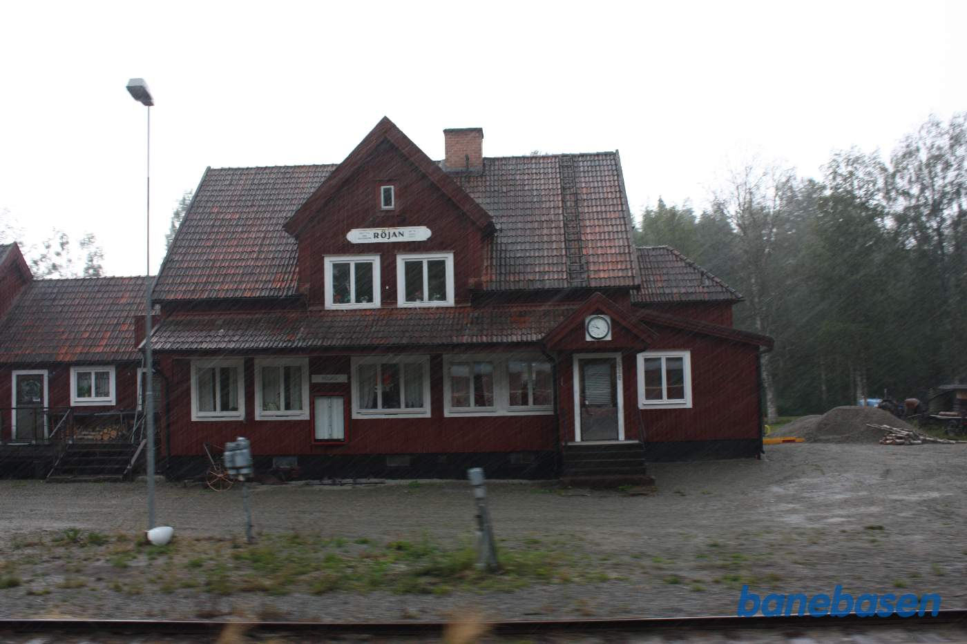 Röjan stationsbygningen i regn, set fra toget