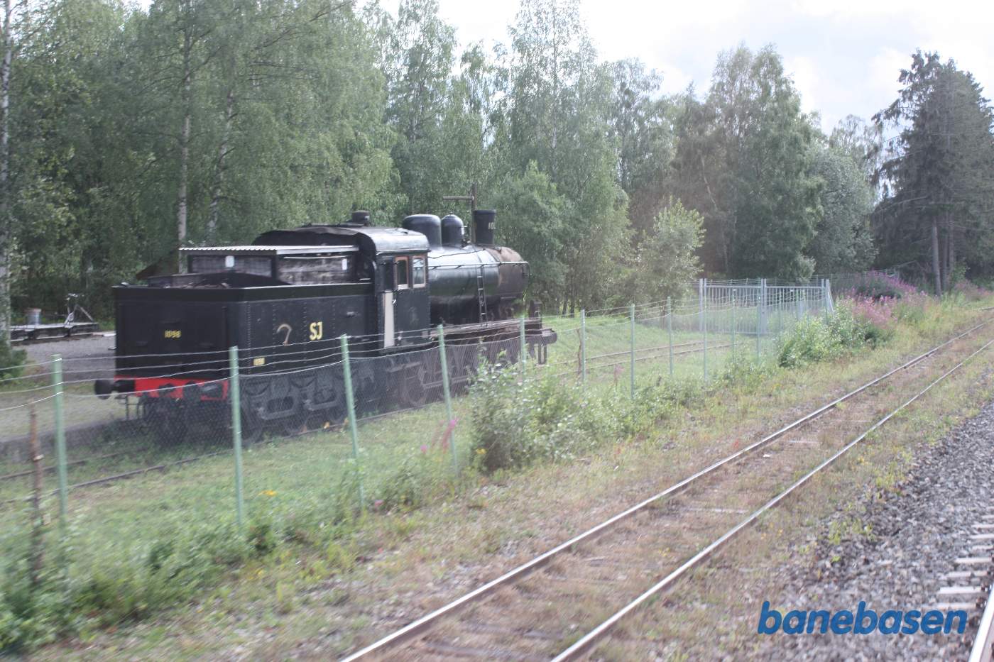 Et damplokomotiv står inde bag et trådhegn