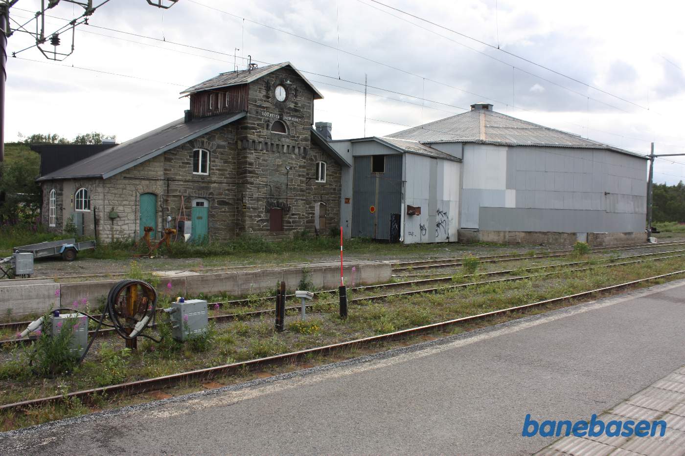 En bygning opført af natur sten samt den overdækkede remise