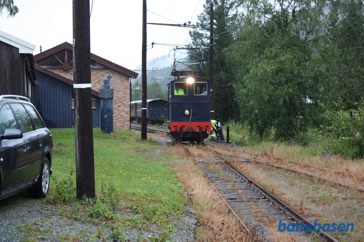 Lokomotivet stoppet efter sporskiftet, personvognene ses i sporet bag lokomotivet, bagsiden af stenremisen ses til venstre