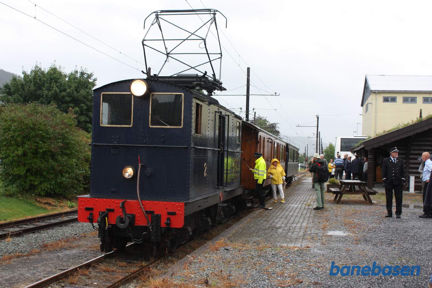 Toget holder ved perron med den lille stationsbygning, opført af træstammer, til højre