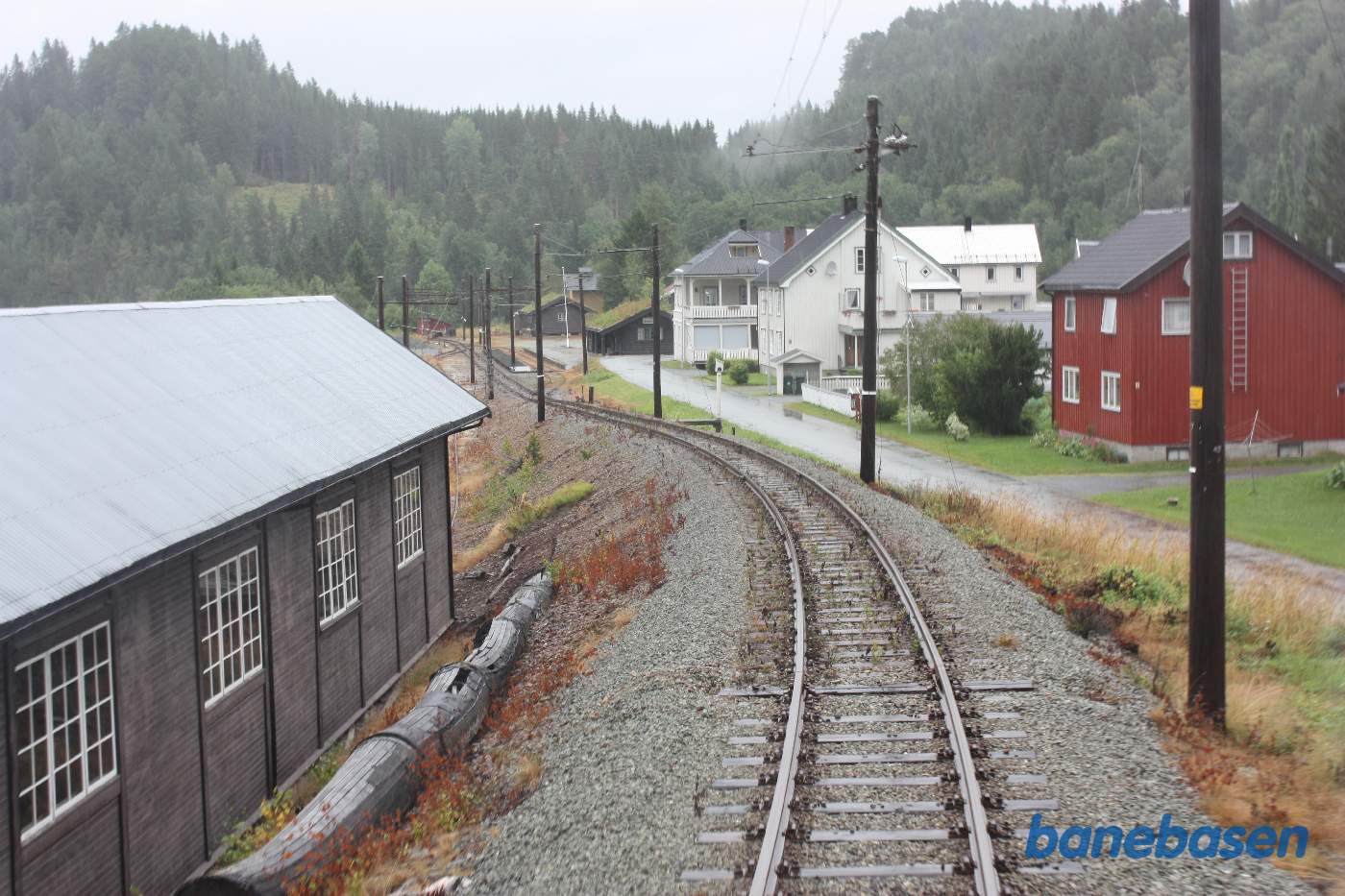 Et bagskud fra bagerste endeperron mens toget suser gennem Svorkmo station, remisen ses nede til venstre