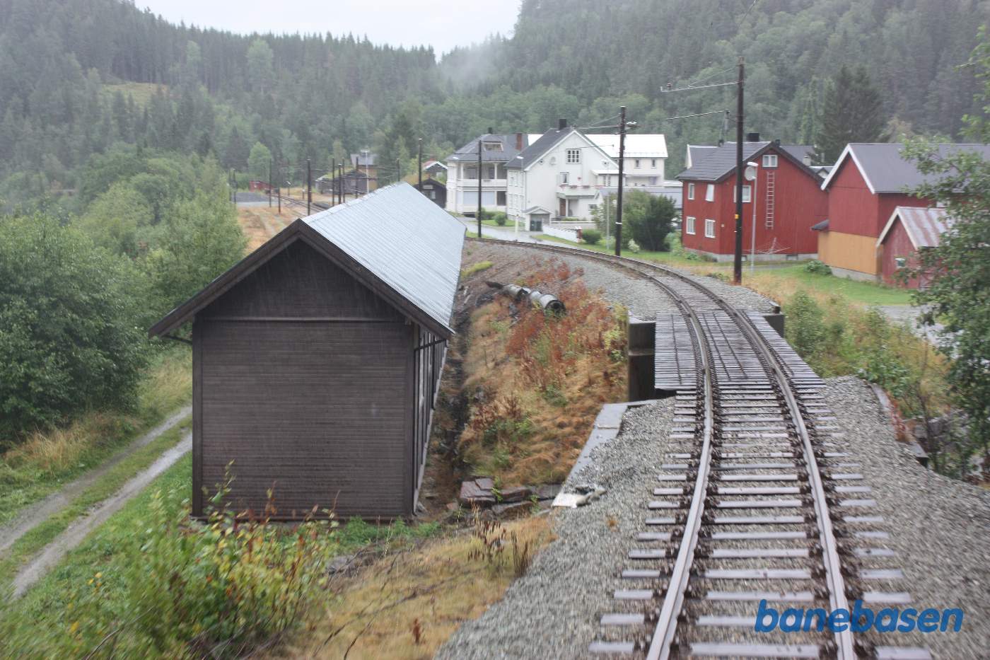 Et bagskud fra bagerste endeperron mens toget suser gennem Svorkmo station, remisen ses nede til venstre