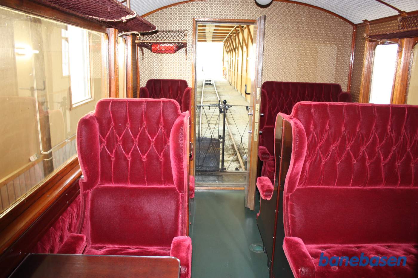 Et billede af en 1.klasses personvogn inde i remisen med flotte røde polstrede sæder