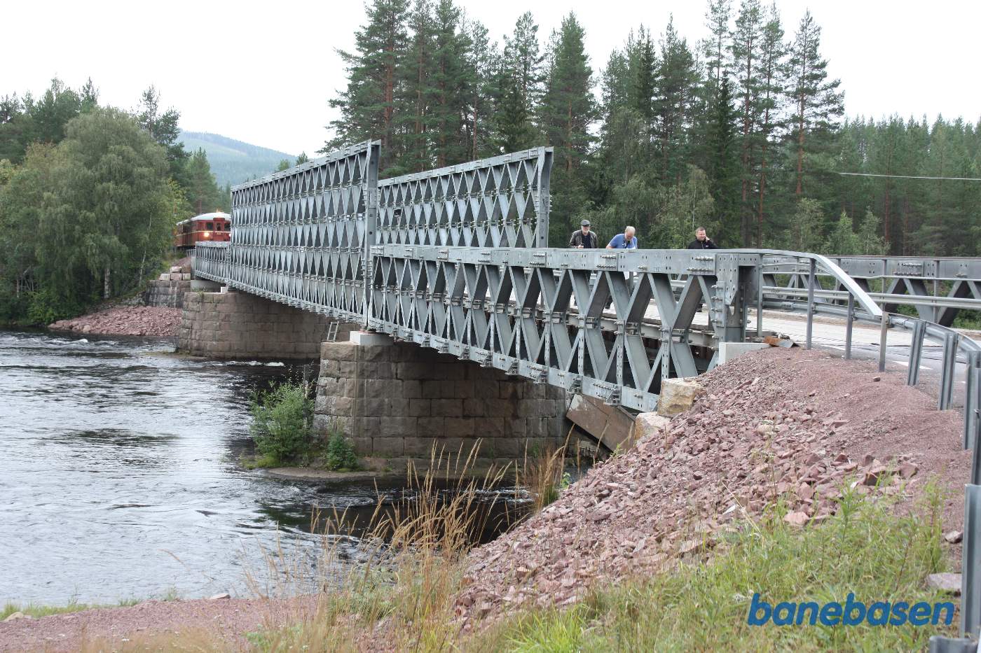 Vi står nede ved elven og kigger på siden af broen og motortoget på den modsatte side