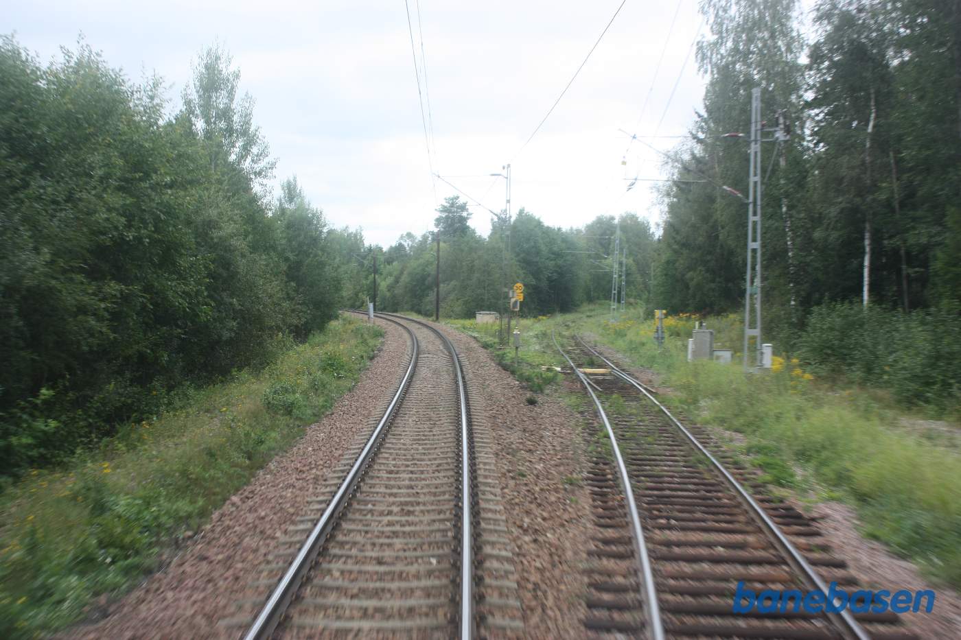 Et bagskud et sted på strækningen mellem Leksand og Gagnef, her kommer banen nede fra en stor tømmerplads ved Insjöns havn ind fra højre