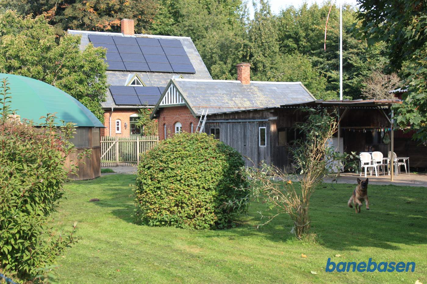 Vi står på Kjærlingsvej og kigger ind i haven med stationsbygningen og pakhuset. Banen løb ude på den anden side af bygningerne