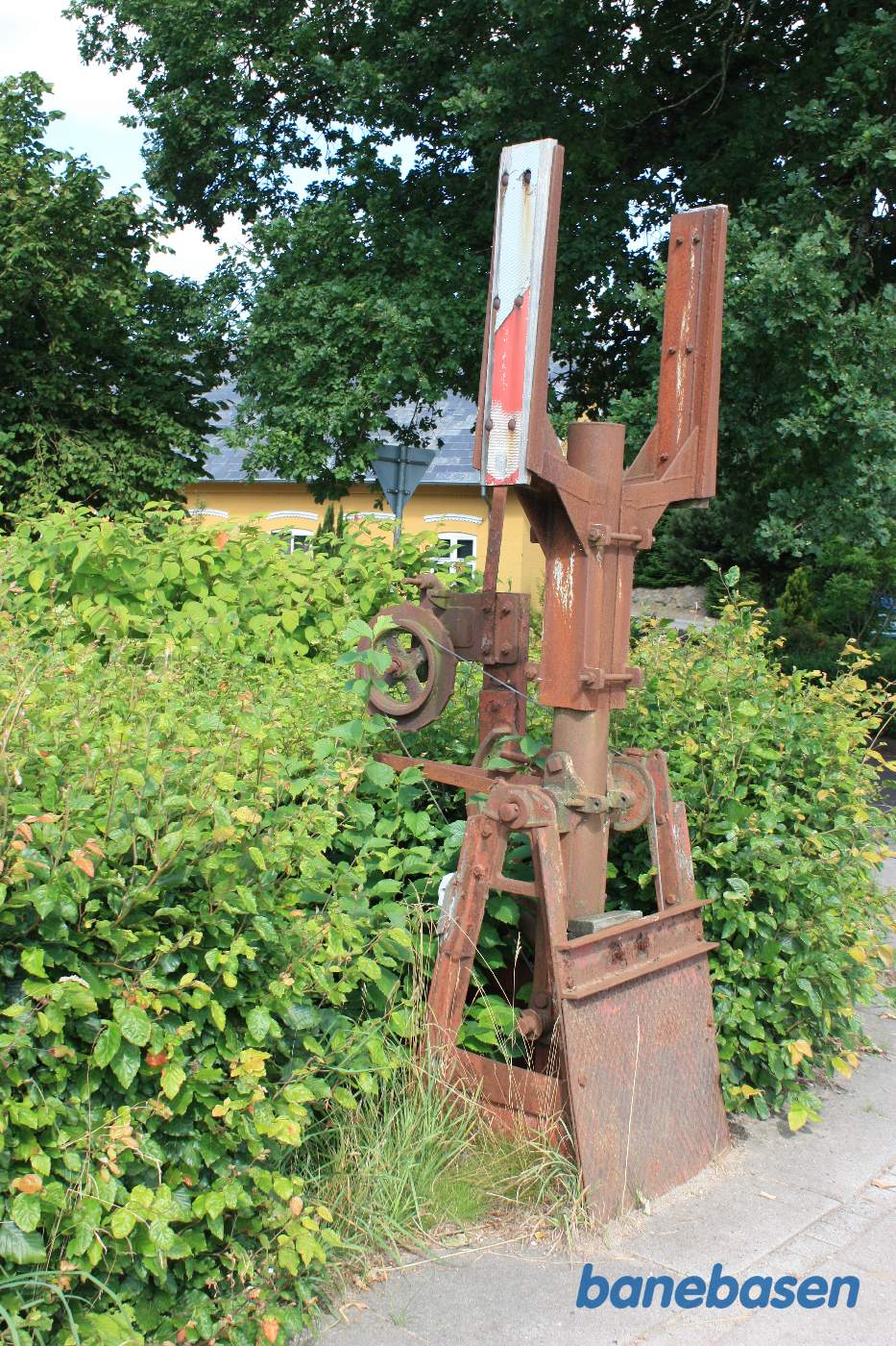 Nærbillede af den ene rustne rest fra vejbommene med wiretræk inde fra stationen