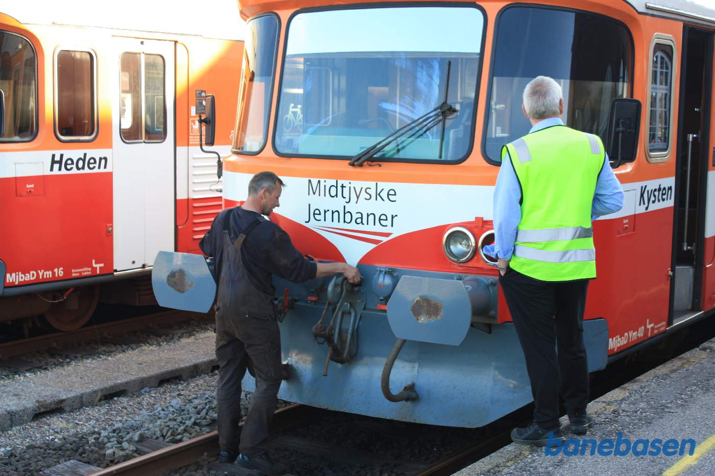 2 Y-tog holder ved perron. En håndværker fra værkstedet skifter pære i den ene frontlygte 2 Y-tog holder ved perron. En håndværker fra værkstedet skifter pære i den ene frontlygte