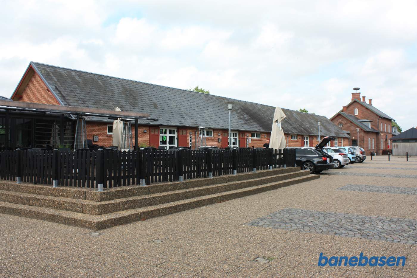 De gamle pakhuse set fra vejen, stationsbygningen i baggrunden