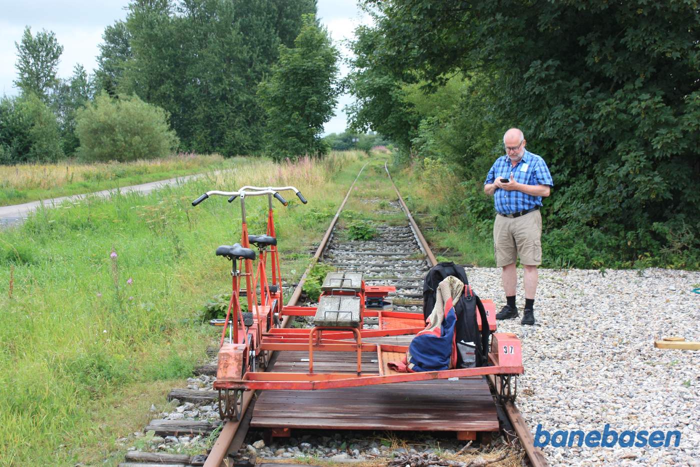 De 2 skinnecykler står klar og en turist tjekker sin mobiltelefon