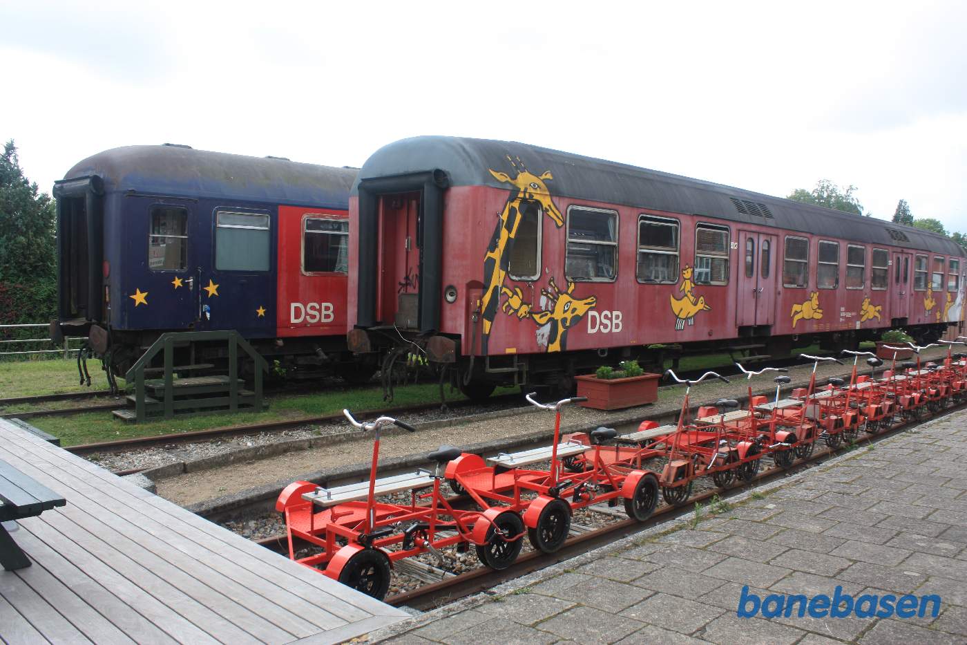 Skinnecykler i perronsporet og en personvogn og en sovevogn i sidesporene