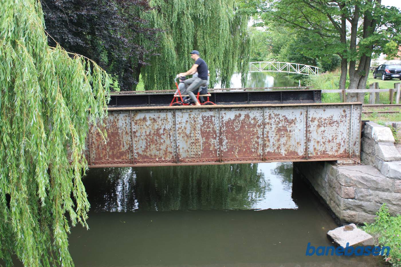 Jernbanebroen over Alling Å set fra siden. Skinnecykel med turister har netop forladt stationen på vej mod Randers