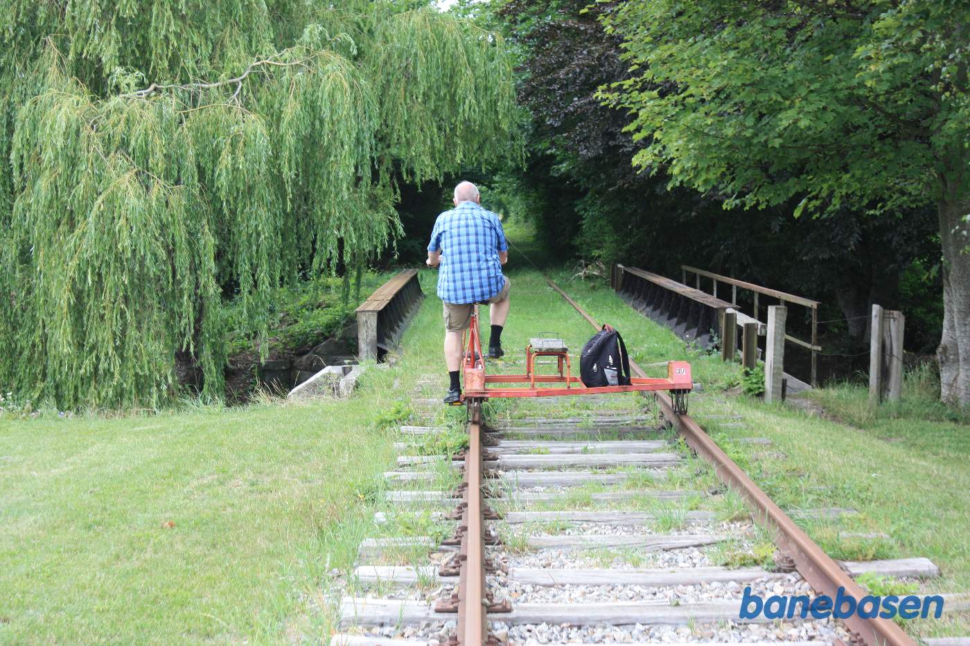 Vi har lige passeret overkørslen ved Rougsøvej, broen over Alling Å lige fremme med cyklist på vej over broen Vi har lige passeret overkørslen ved Rougsøvej, broen over Alling Å lige fremme med cyklist på vej over broen