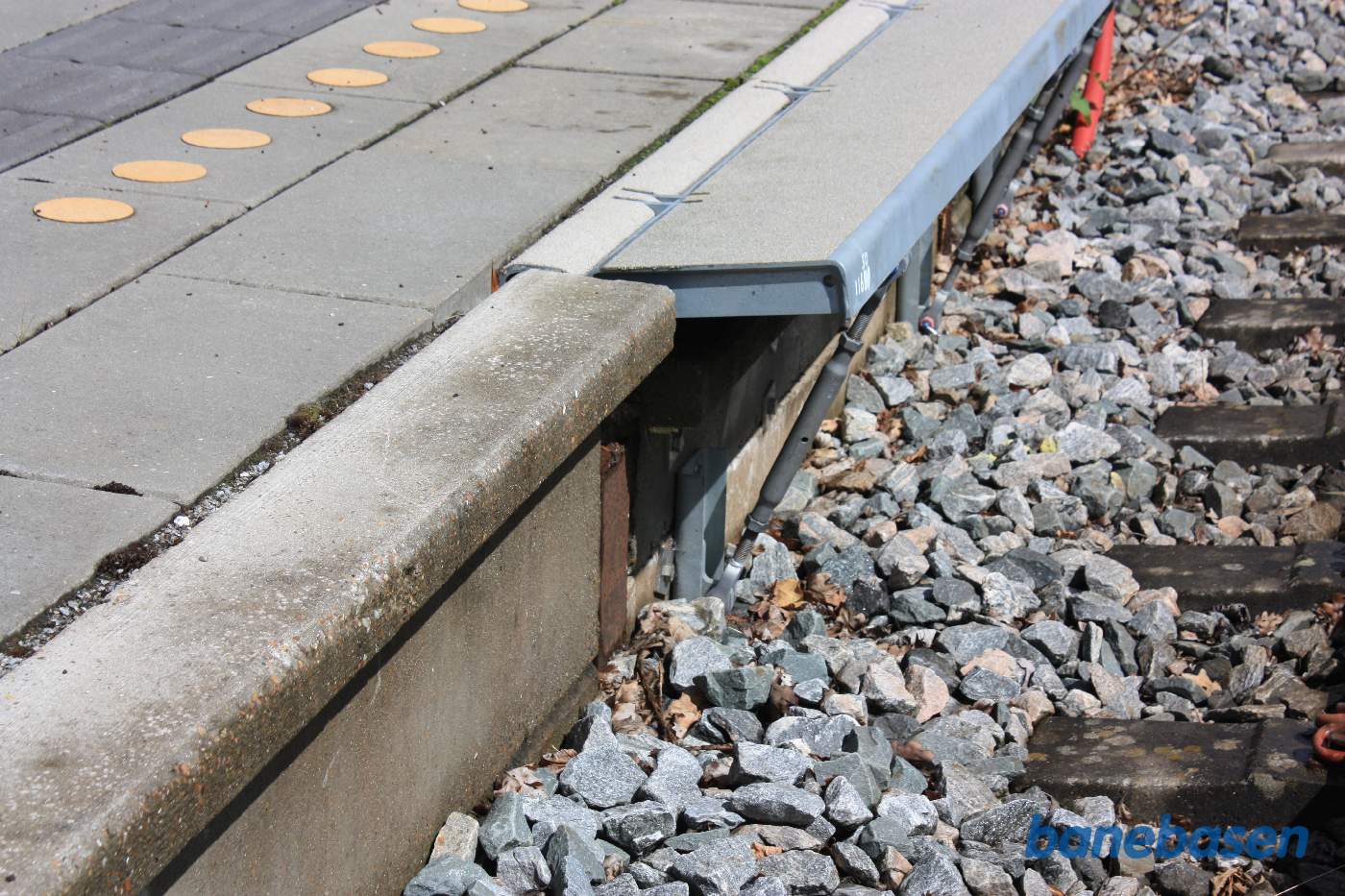 Nærbillede af perronkanten der kan klappes ned, hvis der skulle køre et godstog forbi Nærbillede af perronkanten der kan klappes ned, hvis der skulle køre et godstog forbi