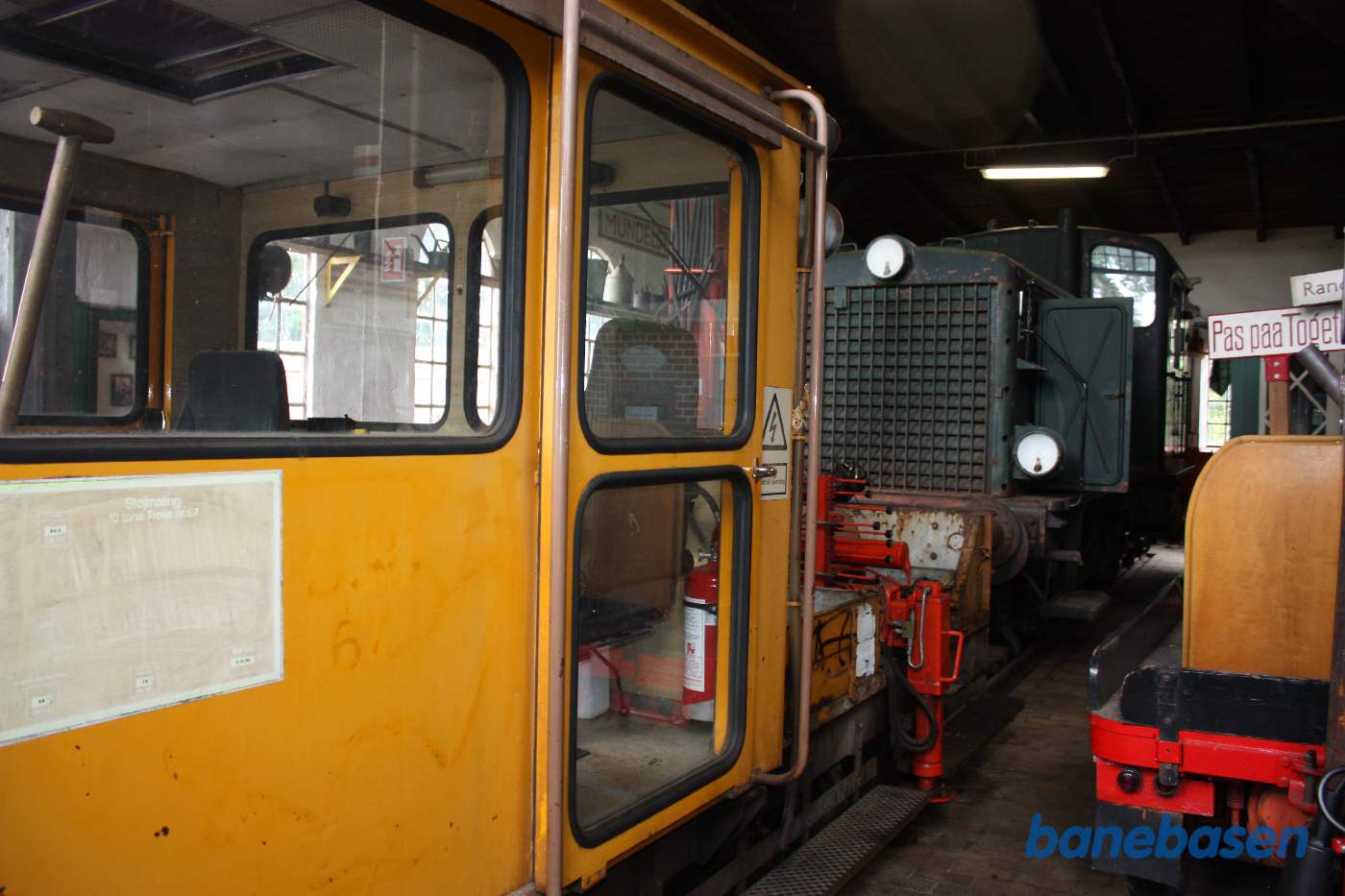 Inde i remisen en gul trolje og et grønt rangerlokomotiv