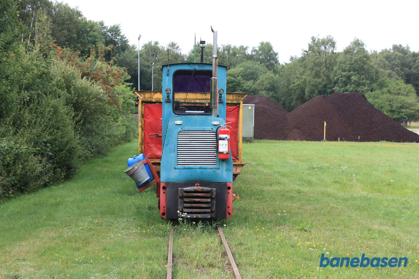 Det lille diesellokomotiv foran vogne til løs mosejord. En bunke mosejord ses til højre Det lille diesellokomotiv foran vogne til løs mosejord. En bunke mosejord ses til højre