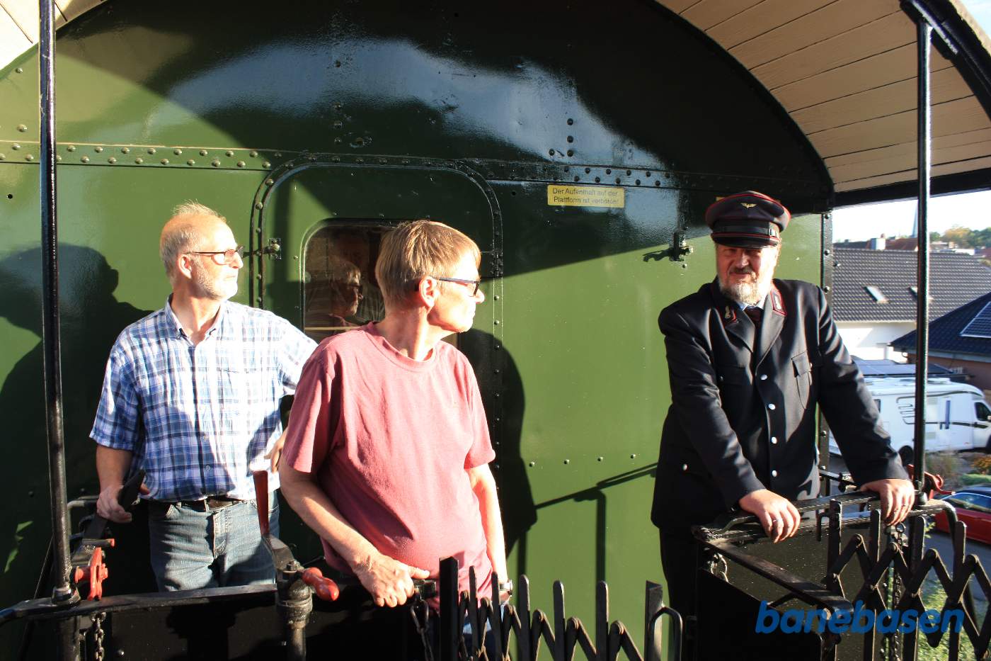 Gæster og personale nyder turen på den åbne endeperron i det bløde aftenlys