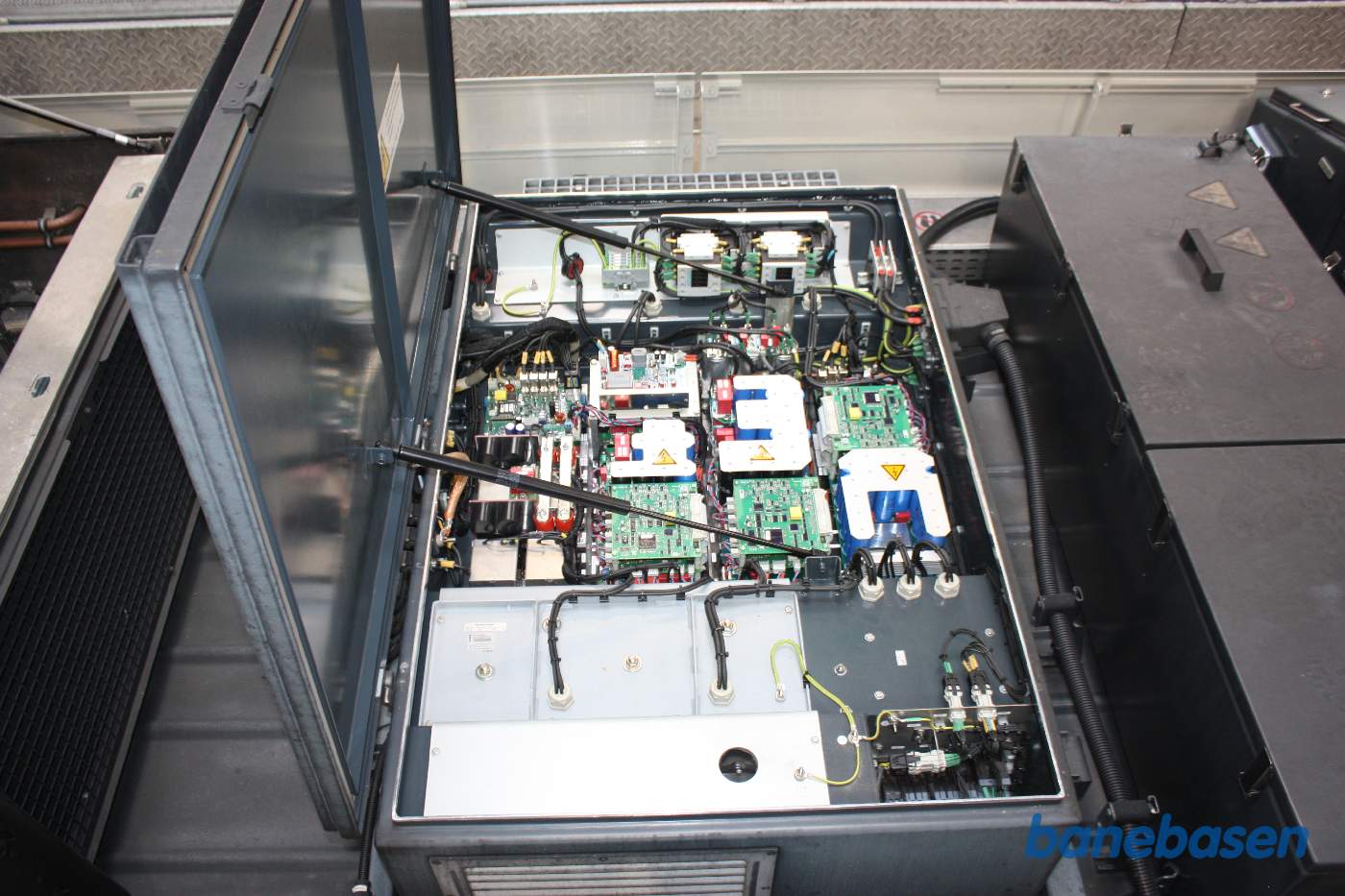 Vi er oppe på taget af et moderne letbanetog og kigger på installationen, her er en af kasserne med elektronik åbnet