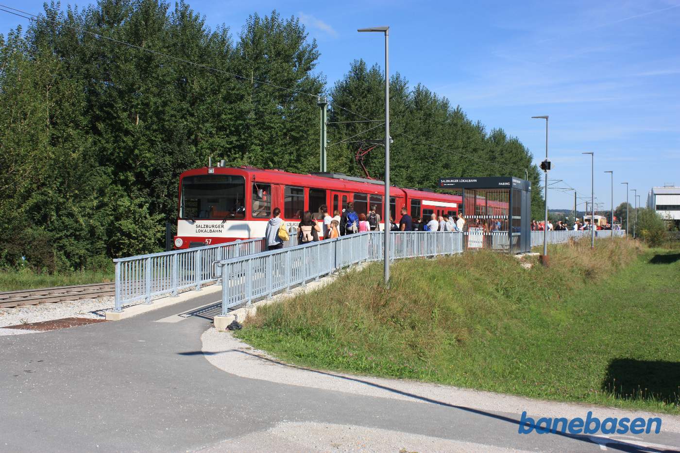 Et anden letbanetog er standset ved trinbrættet og passagererne stiger ud mens andre venter på at komme med