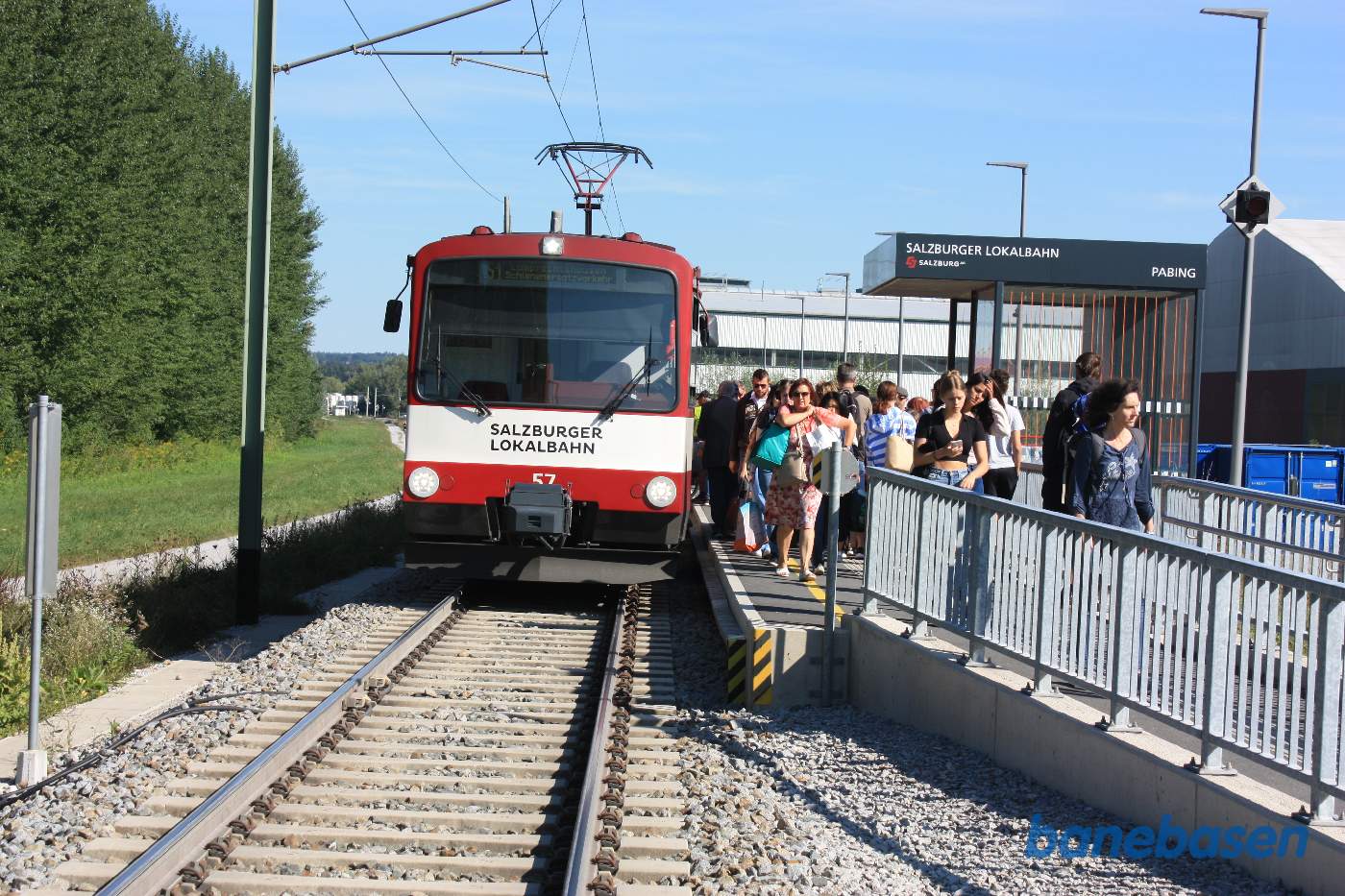 Et anden letbanetog er standset ved trinbrættet og passagererne stiger ud mens andre venter på at komme med
