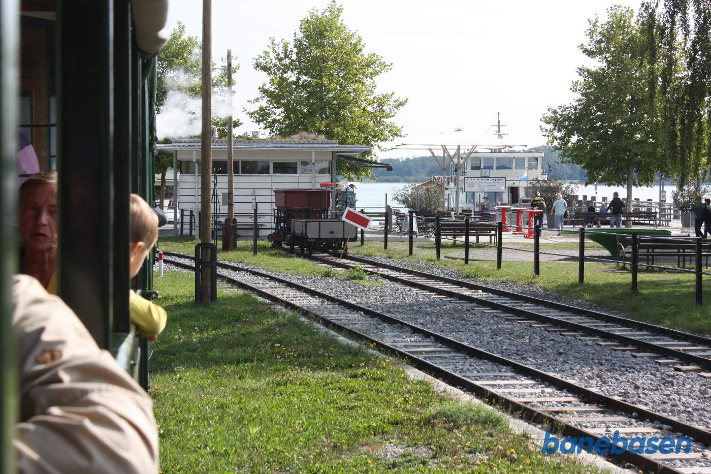 Damptoget på vej ind på stationen, søen ses i baggrunden