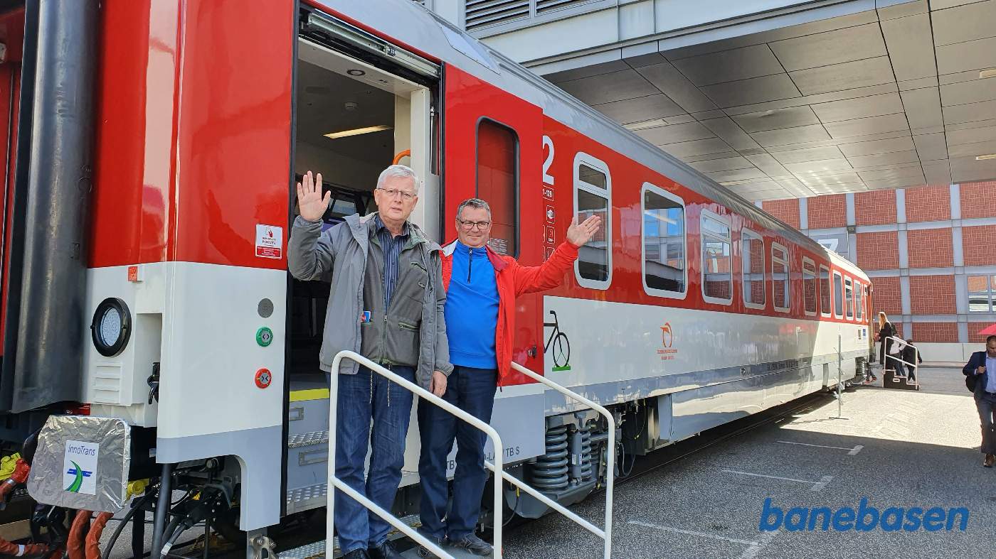 Den nye personvogn set udefra med 2 vinkende gæster