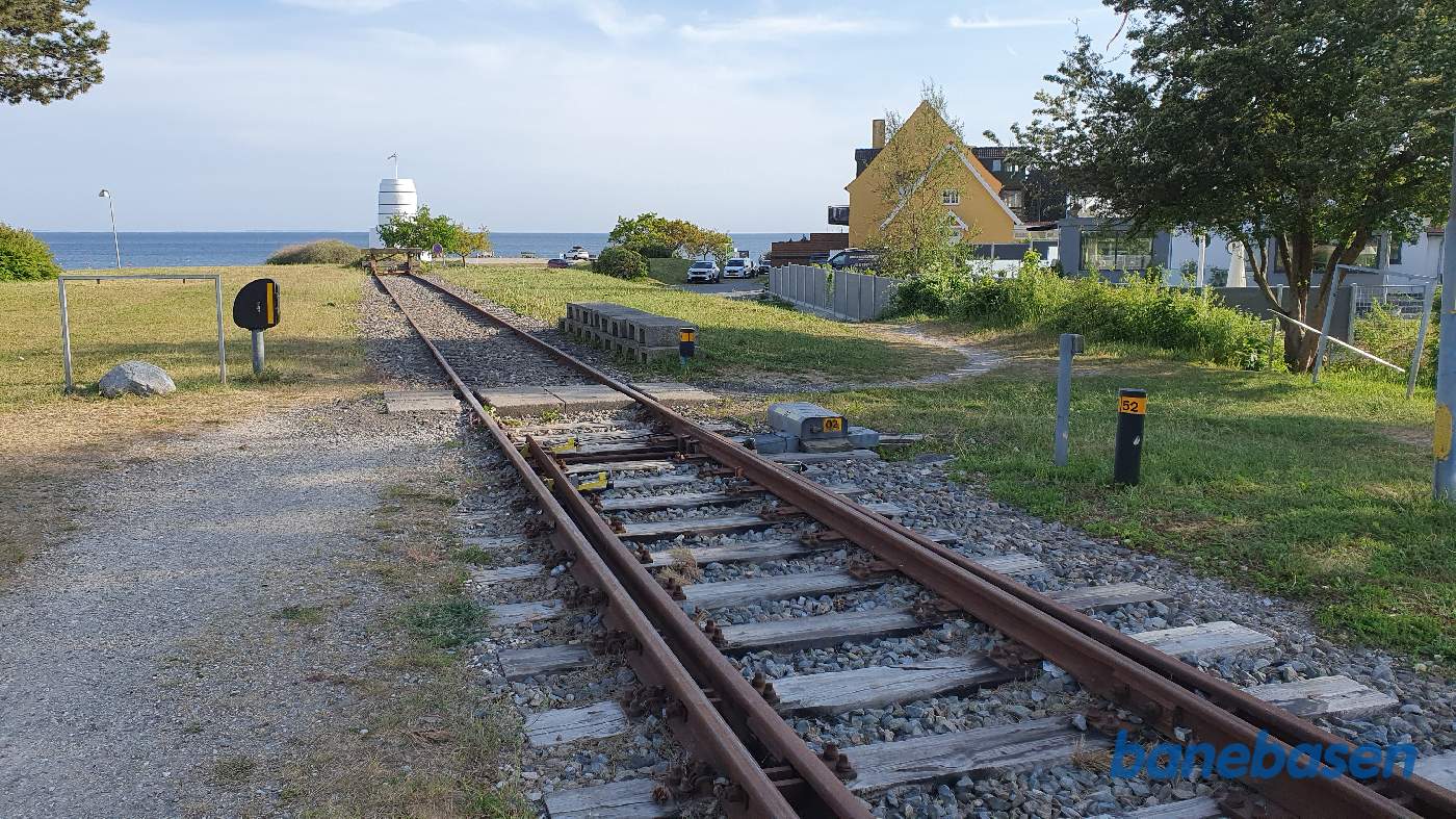 Her ved havet ender banen i en stopbom, havnesporet gik ned i højre side, hvor de to hvide biler holder
