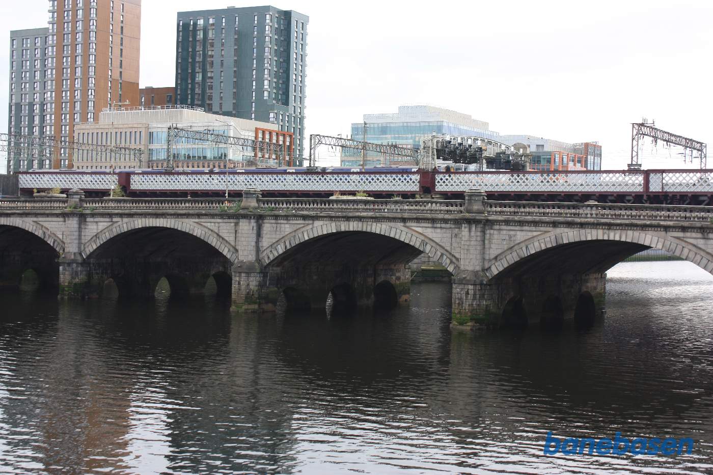 Jernbanen går på en meget bred bro over floden Clyde, broen Glasgow Bridge ses i forgrunden