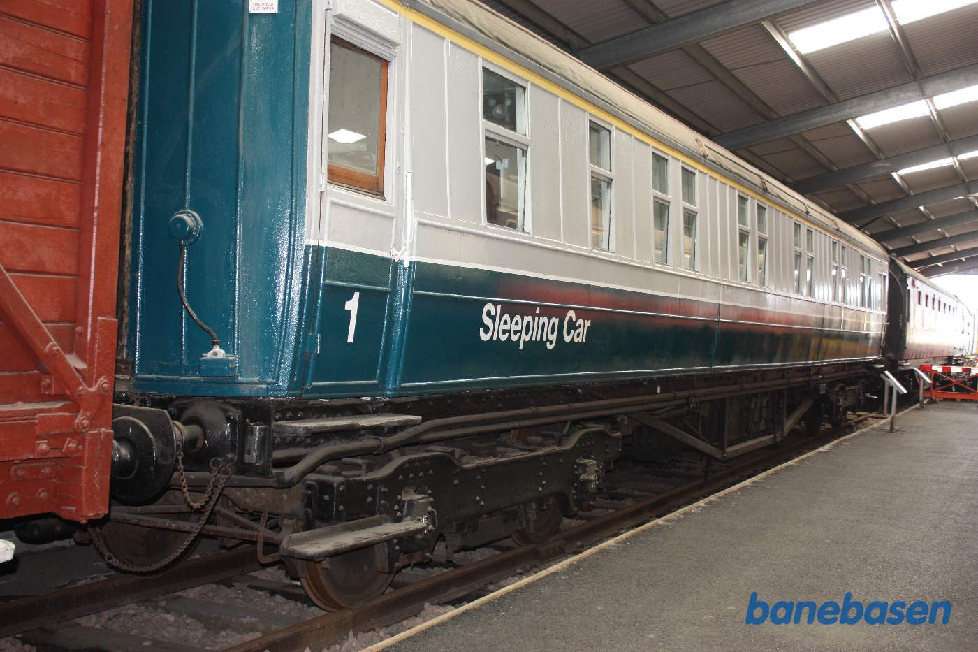 Inde i den store vognhal står lange rækker af rullende materiel, her en sovevogn