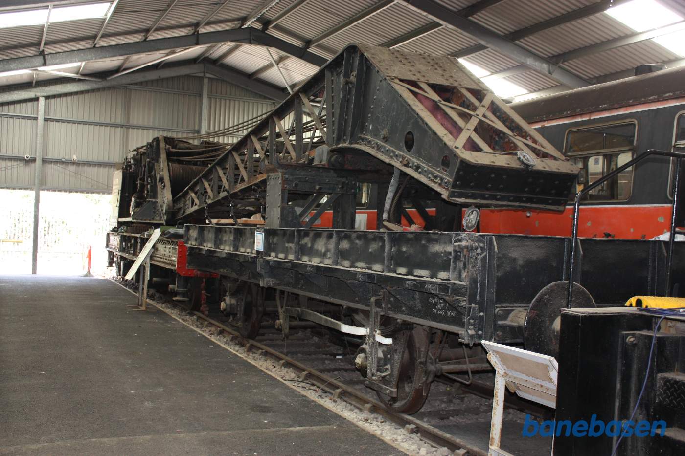 Inde i den store vognhal står lange rækker af rullende materiel, her en stor jernbanekran