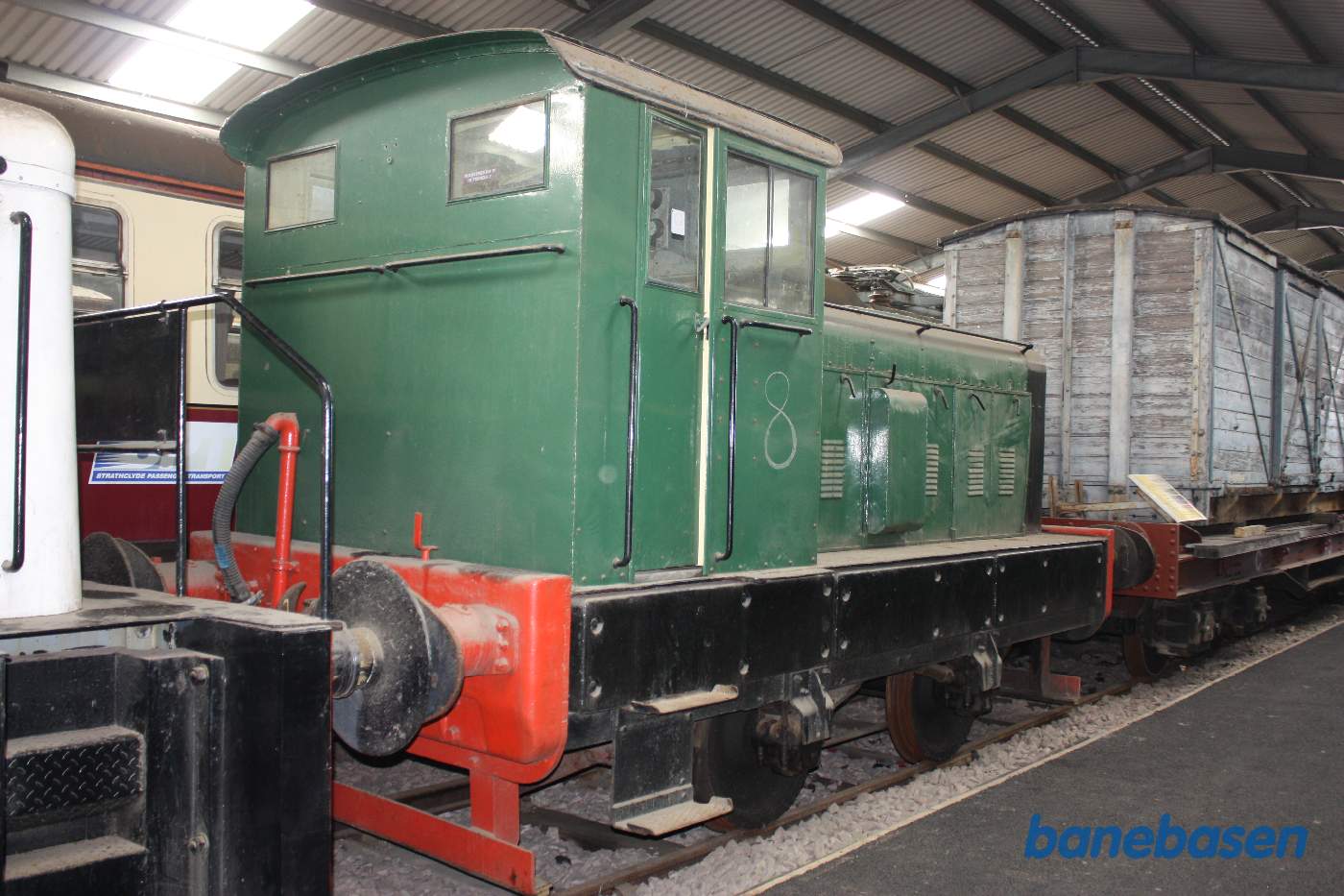 Inde i den store vognhal står lange rækker af rullende materiel, her et lille grønt rangerlokomotiv