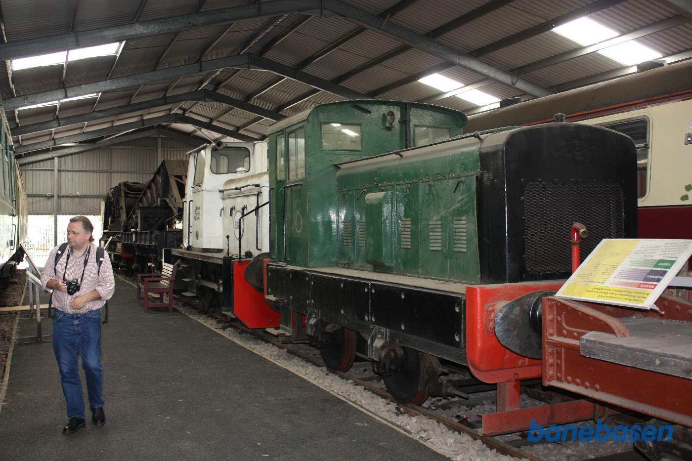 Inde i den store vognhal står lange rækker af rullende materiel, her et lille grønt rangerlokomotiv