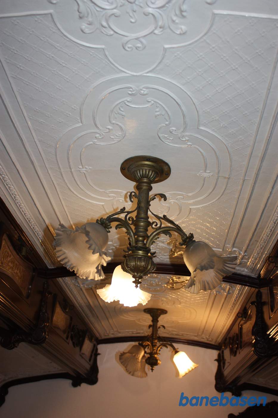Nærbillede af to lysekroner med lys i og et meget flot loft